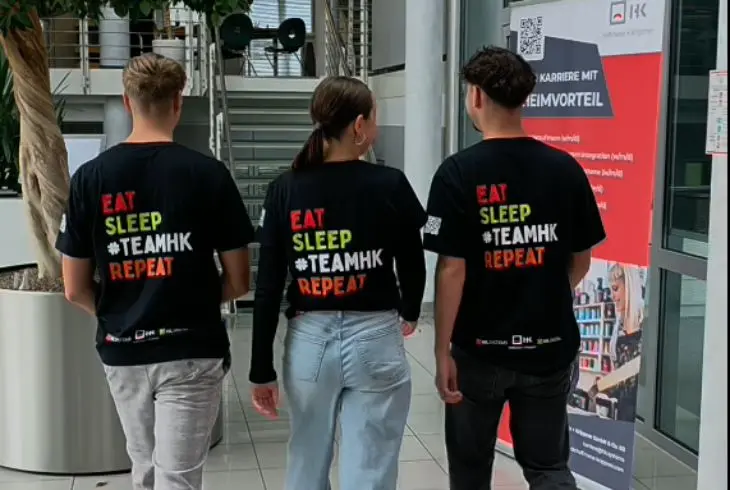 Drei Auszubildende von Hoffmann + Krippner mit #TEAMHK-Shirts von hinten