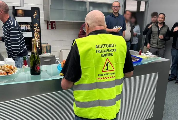 Person mit Warnweste bei einer Abschiedsfeier in der Firmenkueche